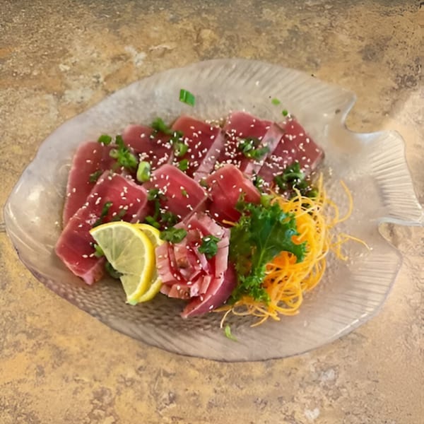 Spikey Ty's tuna sashimi, garnished with sesame seeds, green onions, lemon, and shredded carrots.
