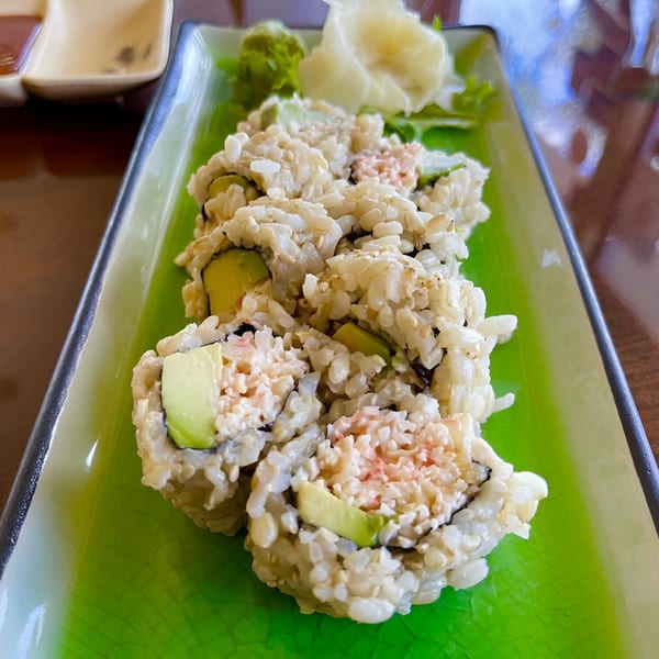 Spikey Ty's Asian sushi rolls with brown rice, avocado, and crab meat on a green plate.