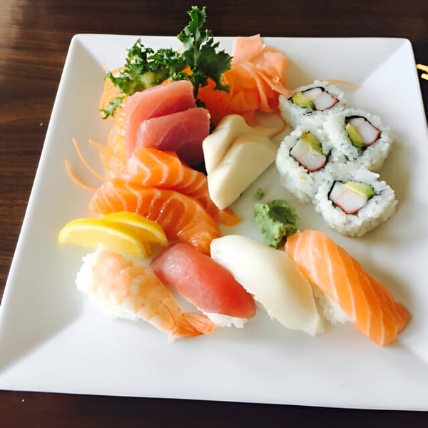A white plate with a colorful assortment of sushi, sashimi, and California rolls.