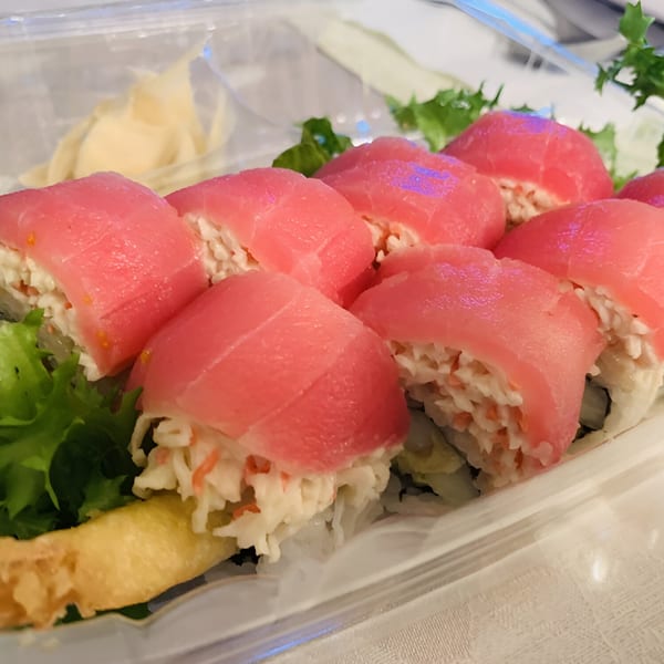 Spikey Ty's tuna sushi rolls with crab meat, lettuce, and pickled ginger in a clear container.